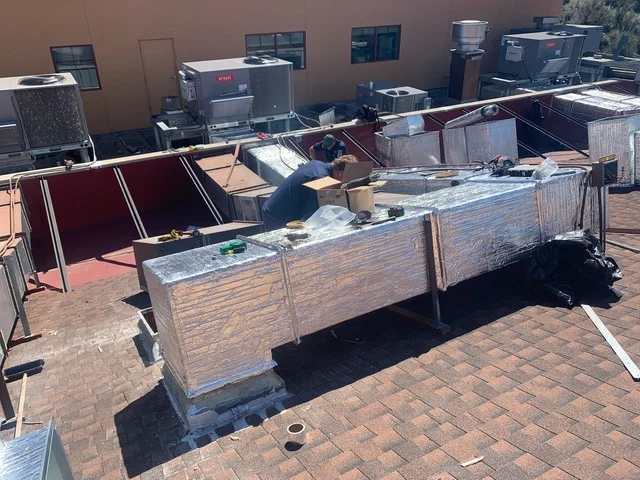 Commercial rooftop with multiple HVAC units, metal ductwork, and equipment staging