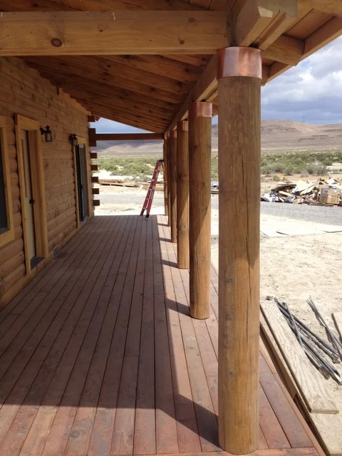 Log cabin interior with exposed beams, wooden deck, and copper HVAC ductwork installation
