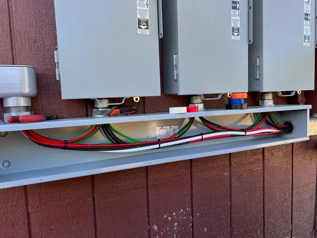 Multiple HVAC units with organized refrigerant lines and electrical connections on exterior wall