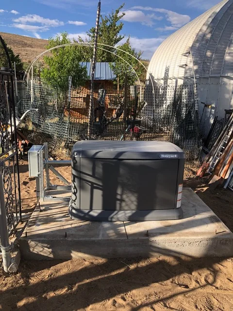 Black heat pump condenser unit installed on concrete pad with metal fencing and arbor structures