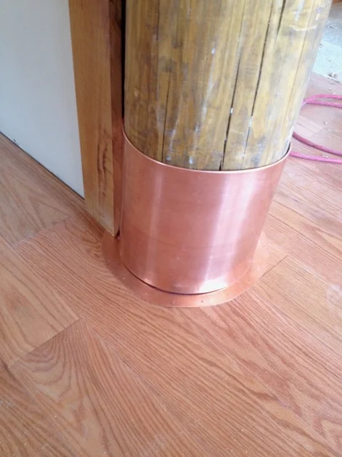 Copper duct wrap installed on round ductwork with wood flooring visible
