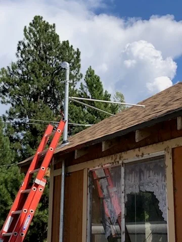 Red ladder against residential home with metal HVAC ductwork and support pole installation