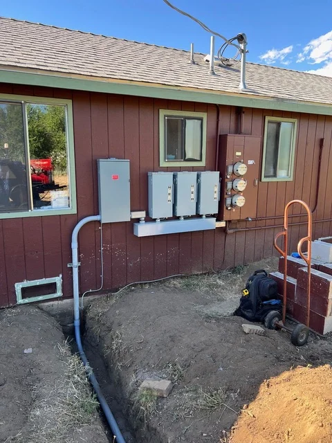 Multiple air handler units mounted on exterior wall with PVC drain lines and electrical connections